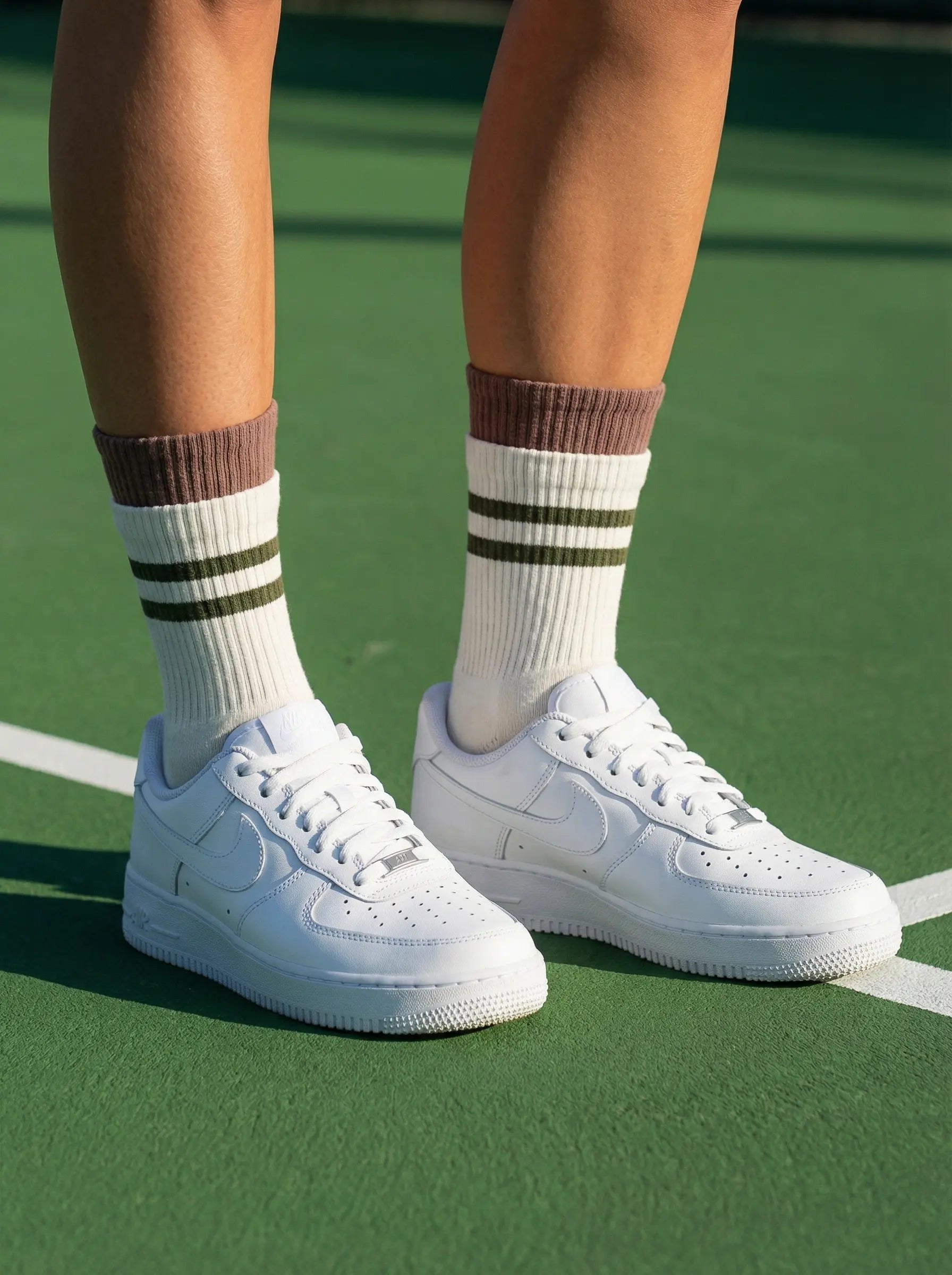 Closeup of layered cuff striped retro grip sock in white colour with green stripe with white sneakers at tennis court front view