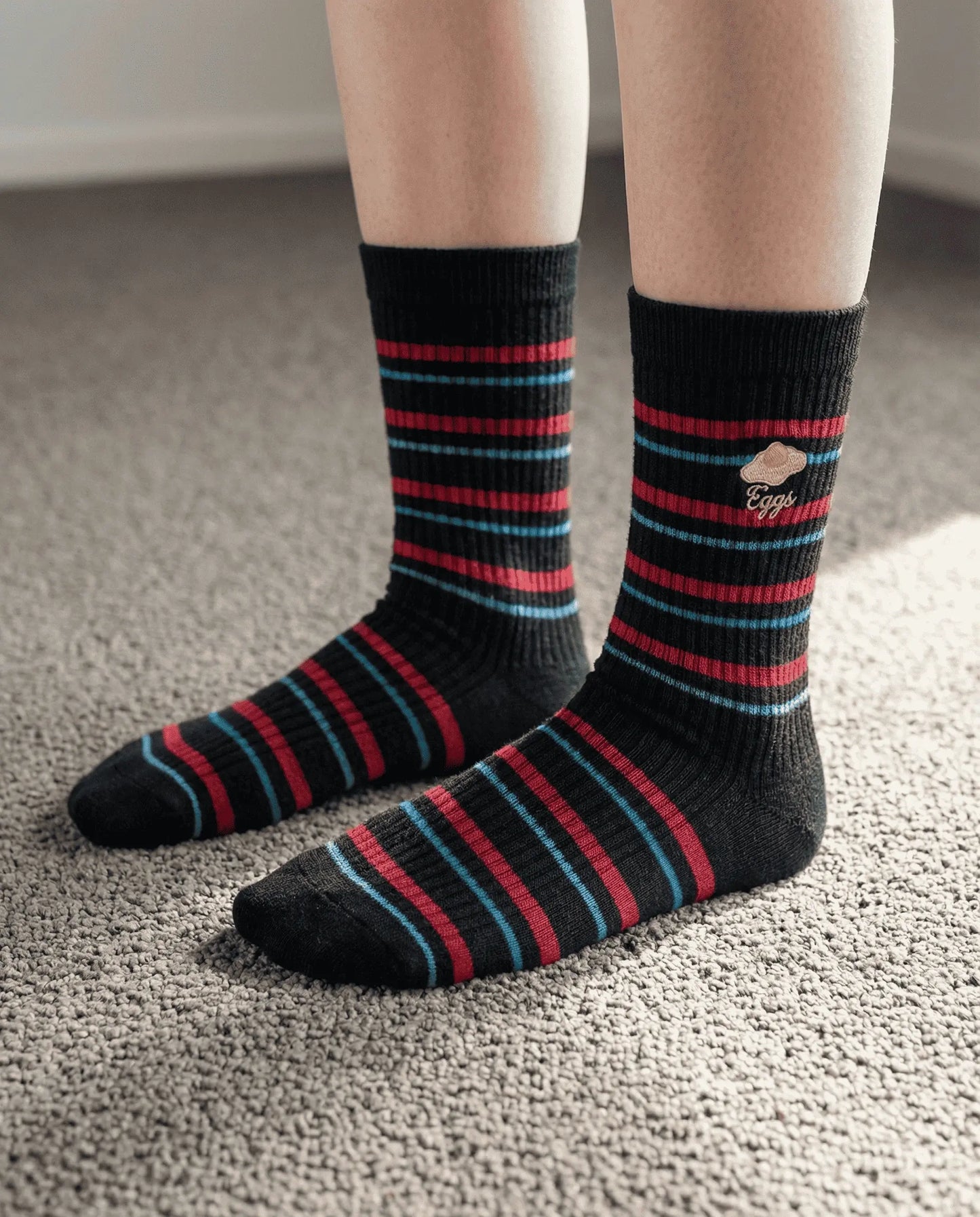 Snack break striped crew sock in black colour with an egg motif try-on on the mat