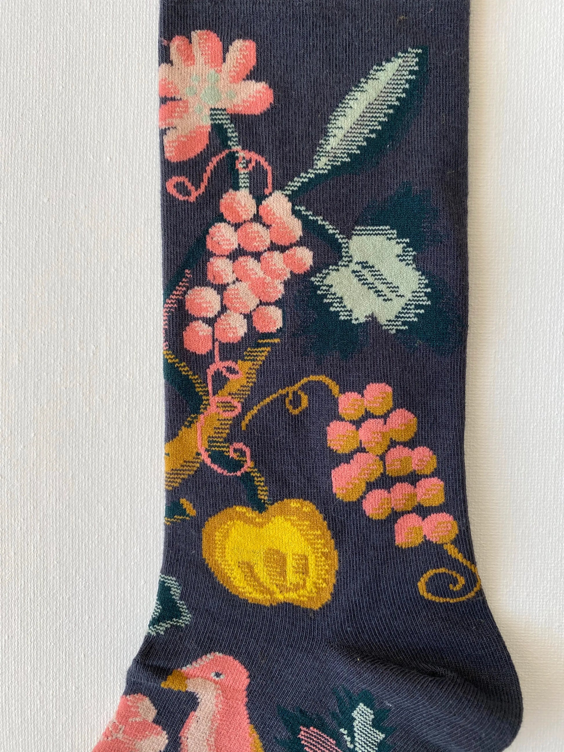 Close up of painted fruits jungle unisex crew sock leg by Sock the Luck up AU