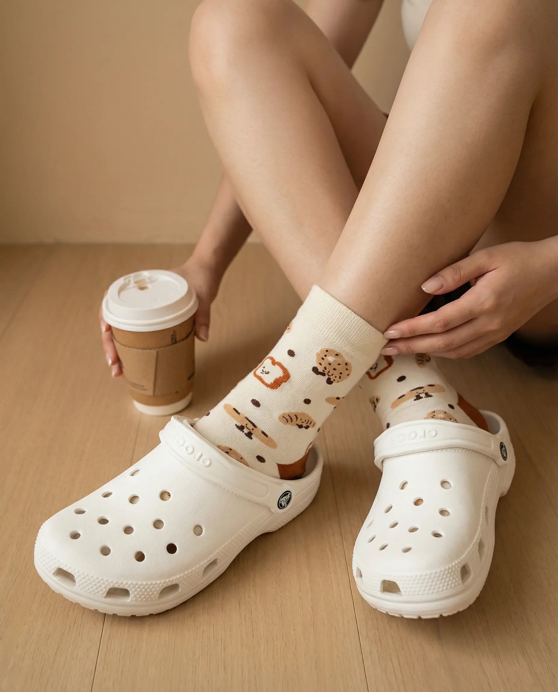 Closeup of pastry delight crew sock try-on with white Crocs clogs top view