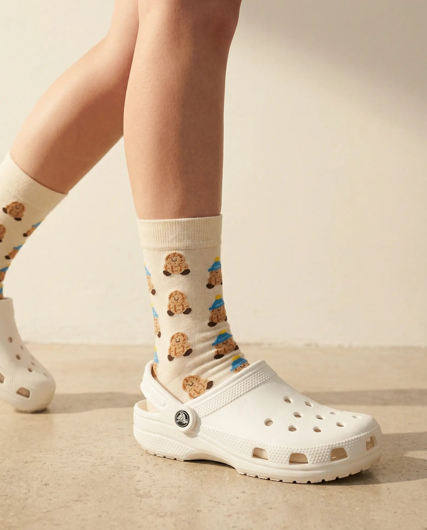Closeup of peanut character crew sock with white Crocs clogs in motion