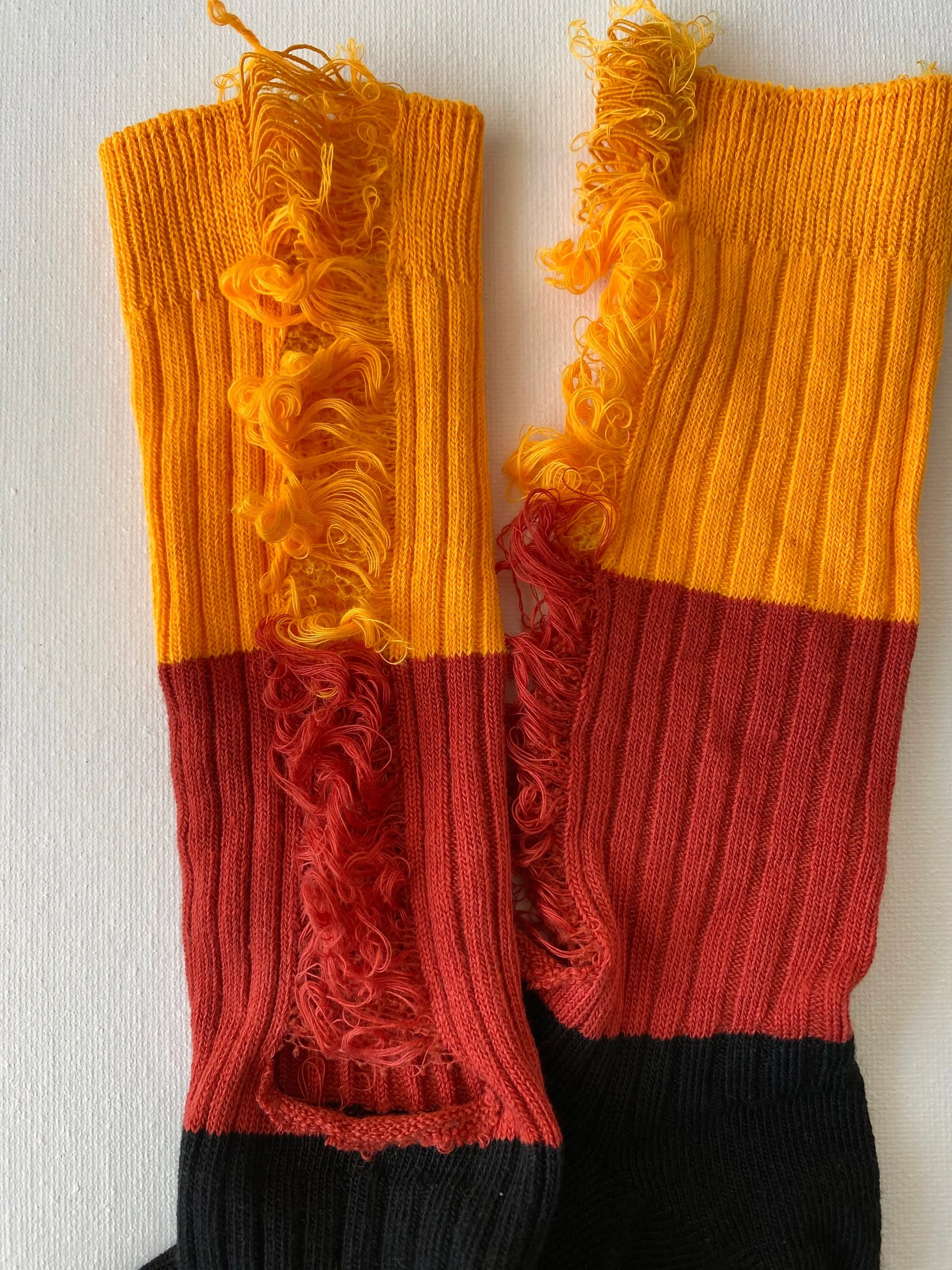Closeup of the ripped details of unisex crew sock in orange and black colour 